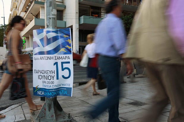 Gregos passam por propaganda eleitoral em rua de Atenas nesta quarta-feira (13) (Foto: AFP)
